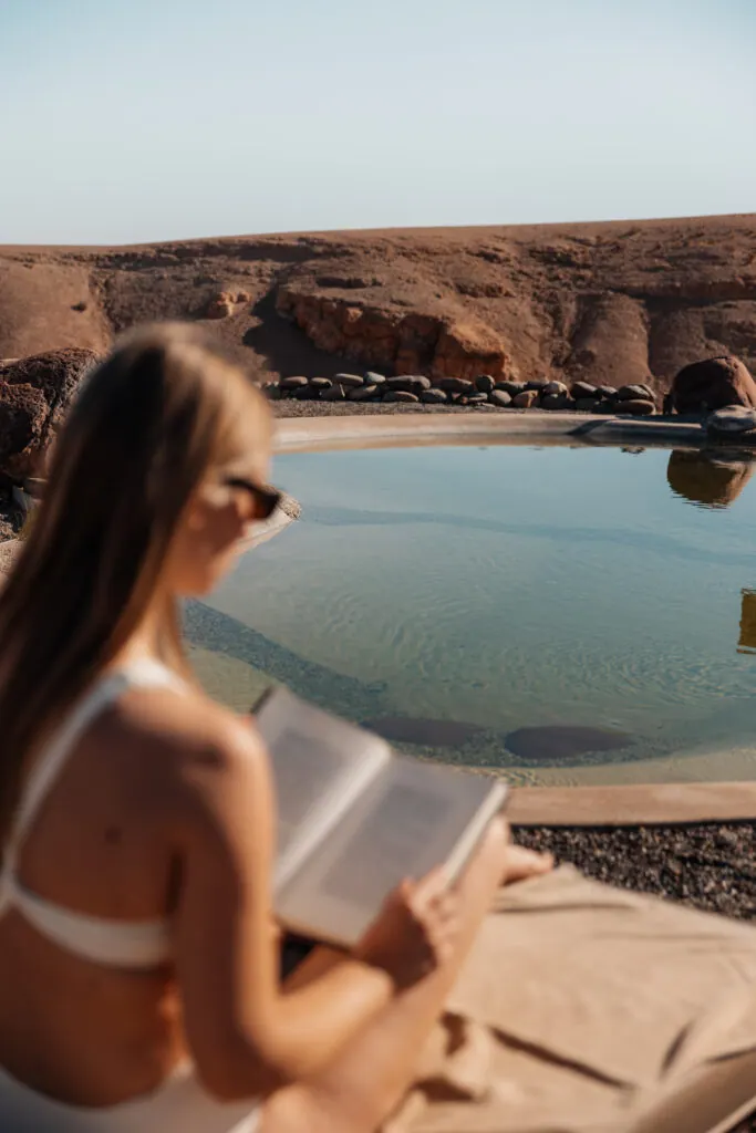 Woman reading by the pool at Inara Camp