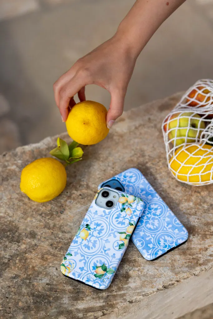 Lemon-print phone cases with fresh lemons on a stone table