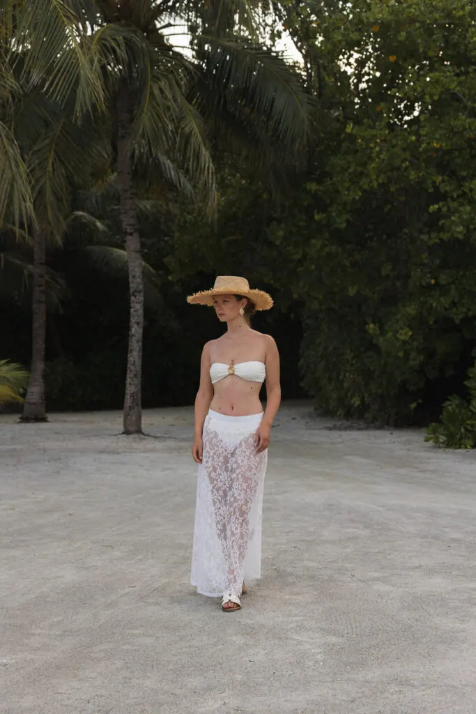 Woman in a straw hat and lace beachwear under palm trees