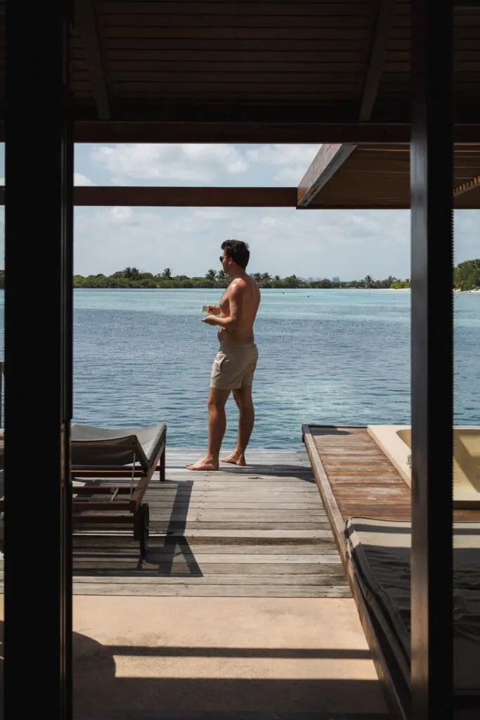 Man looking out over the lagoon from an overwater villa at Villa Nautica, Maldives